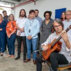 Músico toca violão e é observado por autoridades