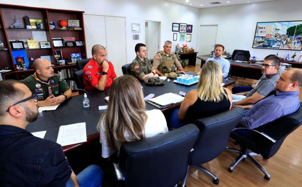 Autoridades reunidas em volta de mesa no gabinete do prefeito