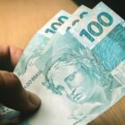 Pessoa não identificada segura três notas de cem reais