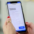 Mulher segura celular com a tela na ouvidoria da Prefeitura
