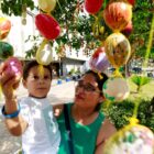 Mãe segura filho no colo que pega ovo de páscoa em árvore