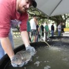 Homem segura peixe em reservatório