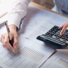 Pessoa faz cálculos na calculadora e preenche planilha