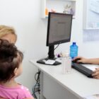 Criança no colo de uma mulher são atendidas na unidade de saúde