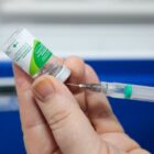 Profissional segura seringa e frasco com vacina