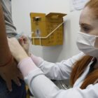 Enfermeira com máscara aplica vacina da gripe em paciente