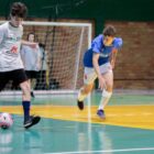 Dois jovens jogam futsal em quadra