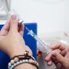 Profissional segura seringa e frasco com imunizante