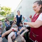 Professora mostra abelha para crianças no pátio da escola