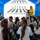 Alunos uniformizados prestam atenção a mulher que dá palestra sobre trânsito