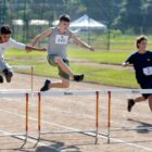 Três meninos participam de competição de corrida com obstáculos