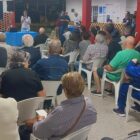 Moradores sentados em cadeiras participam de palestra na comunidade