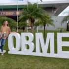 Aluna com medalha posa em frente a local da cerimônia