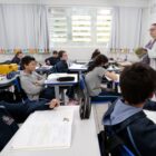 Alunos em sala de aula com professora à frente