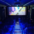 Imagem de uma sala de cinema com telão e cadeiras