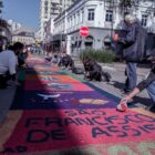 Pessoas trabalham em rua decorando tapetes no chão