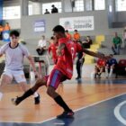 Meninos disputam bola em partida de futsal em quadra
