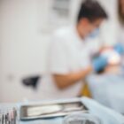 Dentista e auxiliar tratam paciente deitado em consultório
