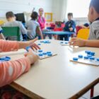 Crianças, em sala de aula, brincam com jogos de tabuleiro