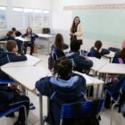 Alunos em sala de aula prestam atenção em professora em pé