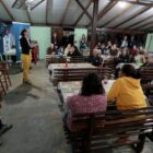 Pessoas reunidas em galpão ouvem profissionais da prefeitura