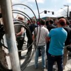 Grupo de pessoas reunidos em frente à poste com cabos enrolados
