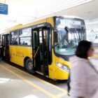 ônibus urbano parado em terminal onde passageiros transitam