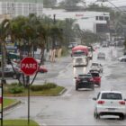 Rua, em dia de chuva, com carros trafegando