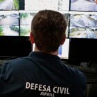 Técnico da Defesa Civil avalia imagens em sala cheia de telas com câmeras
