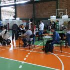 Pessoas sentadas em cadeiras no meio de uma quadra