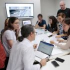 Profissionais da agência francesa e da prefeitura reunidos em volta de uma mesa com computadores