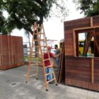 Casas pequenas de madeira sendo montadas em praça