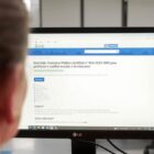 Pessoa olha para tela do computador na página com informações do concurso
