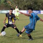 Dois jogadores disputam bola em campo de futebol