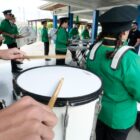 Alunos com instrumentos e roupas de fanfarras se aprensentam