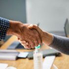 Duas pessoas dão as mãos como gesto de acordo,