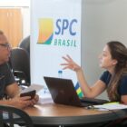 Mulher orienta homem sentados em cadeira ao redor de uma mesa