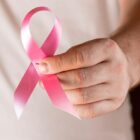 Homem segura laço rosa nas mãos, símbolo da campanha do Outubro Rosa