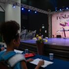 Mulher em palco com faixa de Flor da Melhor Idade sorri para jurados