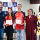 Prefeito, vice e secretária de Esportes posam para foto com dois atletas