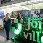 Stand na Festa das Flores com a marca de Joinville visitado por pessoas