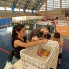 Pessoas organizam doações em caixas dentro de ginásio, com pista de patinação no gelo de fundo
