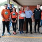 Homens e mulheres uniformizados posam para foto, uma mulher segura o certificado
