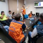 Gerente da Defesa Civil mostra dados em telão em pé, em sala de reunião, com outras autoridades sentadas observando