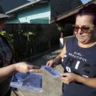 Agente de saúde entrega material informativo para mulher