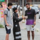 Aluno com uniforme e outro vestido de mosquito entregam folheto para homem na rua