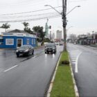 Avenida com quatro pistas, um canteiro no meio e carros trafegando