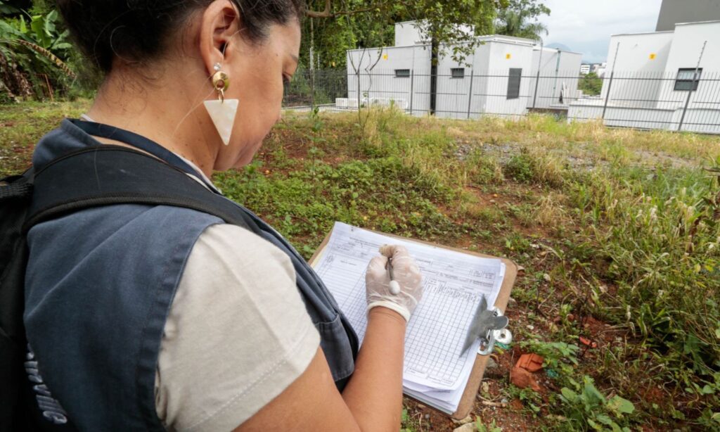 Mulher agente de combate a endemias escreve em prancheta