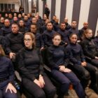 Homens e mulheres de uniforme azul escuro sentados em plateia