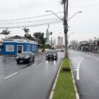 Rua com quatro pistas, canteiro no meio delas e dois carros trafegando